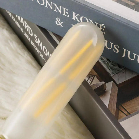 Close-up of a dimmable 6W tubular LED bulb, 60W equivalent, frosted finish, on a soft surface.