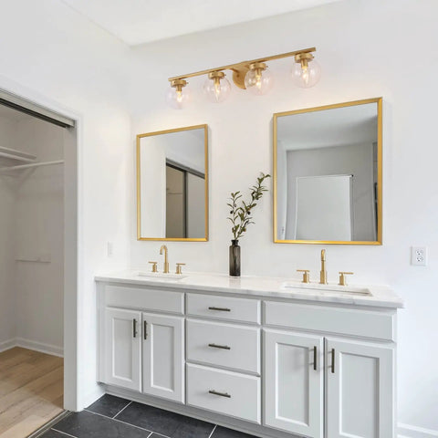 Gold Bathroom Vanity Light 28 Inch Four Light Fixture With Clear Glass Globes, Hand Painted Gold Finish, in a modern bathroom.