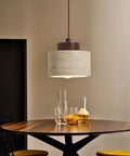 Modern Mini Pendant Light, Travertine Stone Light Fixture with Wooden Accent above a dining table, ambient lighting.