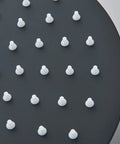 Close-up of matte black 8-inch round shower head with white nozzles from Matte Black Shower System With 8 Inch Round Shower Head And Handheld Spray Brass Rough In Valve Durable Stainless Steel Hose And Complete Trim Kit For No Fuss Installation.