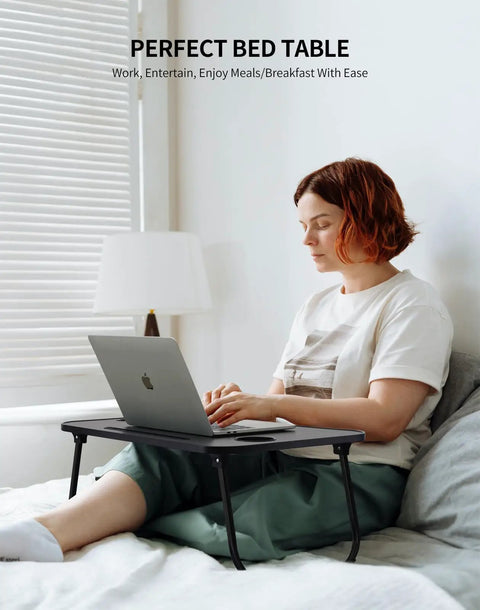 Person using Foldable Laptop Bed Desk With Cup Holder, Tablet Slot And Lifting Handle, Portable Lap Table for work on bed