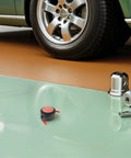 Compact Automatic Aerosol Fire Extinguisher Kit For Car Engines And Garages, two fire suppressors beside a car tire in a garage.