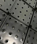 Close-up view of Black Plastic Pegboard Wall Organizer Panels, 4 Pack of 17.5x17.5 Inches, showing stand-off design and holes.