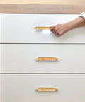 Sleek Dope Solid Wood Cabinet Pull Handle Set For Cabinets, 96mm Aluminum Wood Bar Pull With Gold Finish, shown on white drawers