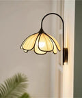 Nordic Floral Petal Wall Sconce Fabric Shade Wall Light,Warmth with a gold petal shade and elegant black metal arm, mounted on a wall.
