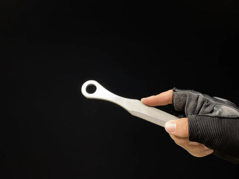 Kunai Inspired Throwing Tool With Full Tang Stainless Steel Build held in gloved hand, showcasing lightweight design.
