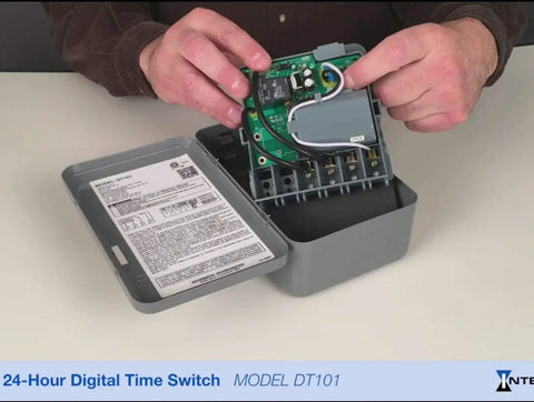 Person handling open DT101 20 Amp 24 Hour Digital Time Switch, SPST, 1 Circuit, showing internal components and manual.