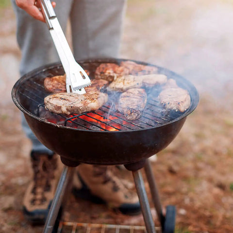 Stainless Steel Barbecue Utensil Set With Carry Bag Professional Grill Tools in use on charcoal grill, cooking steaks outdoors