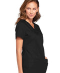 Woman wearing Women's Slim Fit V-Neck Scrub Top With 3 Pockets And Instrument Loop, Fade-Resistant Fabric, Black, Size M, side view.