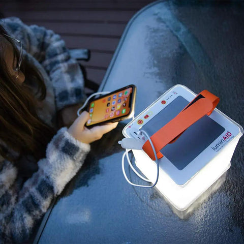 Person charging phone with 2 In 1 Solar Camping Lantern And Phone Charger with 300 Lumens of Bright LED Light, inflatable outdoor lamp.