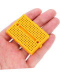 Hella Handy Six Piece Solderless Breadboard Kit For Circuit Prototyping And Science Experiments Featuring Quick Hookup Points, compact orange breadboard in hand.