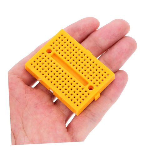Hella Handy Six Piece Solderless Breadboard Kit For Circuit Prototyping And Science Experiments Featuring Quick Hookup Points, compact orange breadboard in hand.