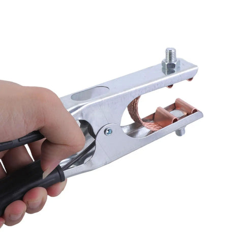 Hand holding a multifunction 500A ground clamp with ergonomic grip for TIG plasma cutting and stable connections.