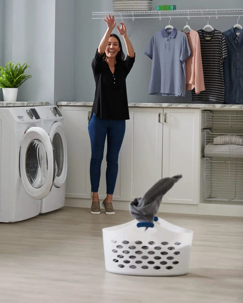 Woman in laundry room using 1.5 Bushel Portable Laundry Basket With Flexible Design Durable Build And Easy One Hand Carry Handles Grab And Go Convenience