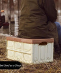 Heavy Duty Collapsible Storage Bins With Lid being used as a stool outdoors while a person sits on it.
