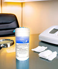 Container of electronics surface wipes on desk, next to magnifying glass and tissue, labeled "Envirocare Surface Wipes."