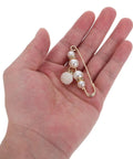 Pearl pin style waist tightening clip held in hand, ideal for jeans and dresses, delivering a snug custom fit.
