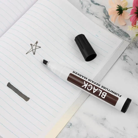 Scratch Fix Marker Pen For Wood Floors And Furniture, black, shown on notebook with cap off, with star doodle.