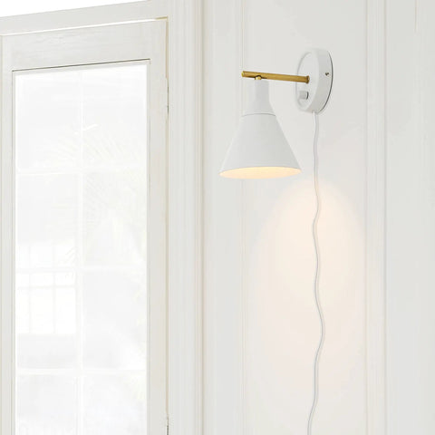 Dope Lofty Chic Modern Matte White Wall Sconce With Brass Accent mounted on wall near a window, fabric cord visible
