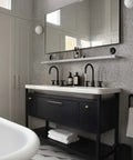 Modern bathroom with gray cabinets, wall-mounted mirror, and black vanity with brass knobs