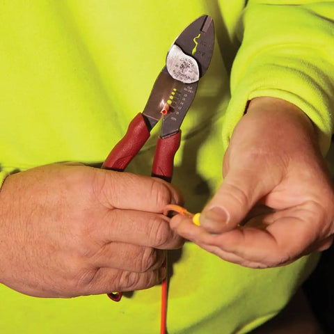 Person using USA Made Wire Cutter, Stripper, and Crimp Tool With Shear Cutter on electrical wire, close-up of tool in hand.