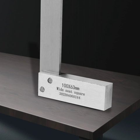 Angled front view of steel machinist square, L-type, 100x63mm wide-seat right-angle measuring tool on wood surface.