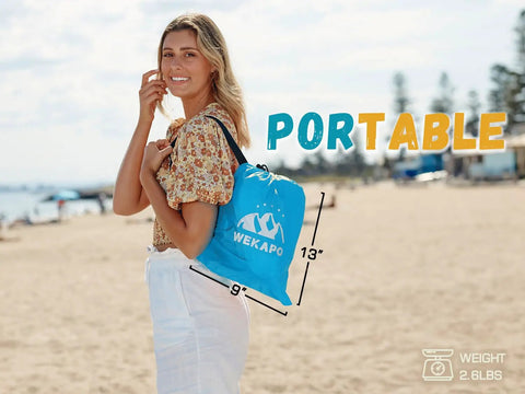 Woman carrying a portable bag containing Inflatable Couch Air Lounger Chair For Camping And Beach Trips on a beach.