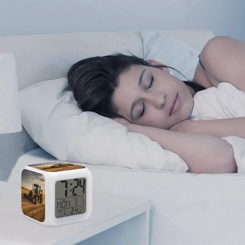 Sleeping woman beside Farm Tractor Alarm Clock With LED Display, Seven Color Night Light, Sleep Training, Sound Machine, And OK To Wake Feature.