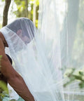 Person setting up Mosquito Net Bed Canopy With Princess Lace, White Four Corner Support, for Twin to King, outdoor scene