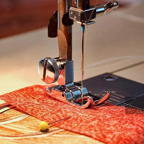 Close-up of a silver snap-on presser foot on a domestic sewing machine with red fabric underneath (zigzag/straight stitch)