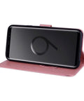 Smartphone in pink leather flip cover, standing horizontally, showing front view with screen facing forward.