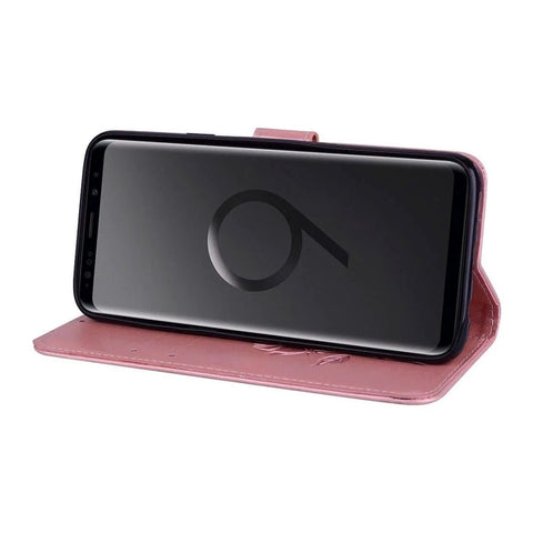 Smartphone in pink leather flip cover, standing horizontally, showing front view with screen facing forward.