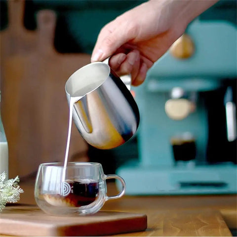 Hand pouring milk from a stainless steel pitcher into a glass cup next to an Electric Coffee Maker With Auto Milk Frother For Smooth Cappuccino Sips Transparent Water Reservoir Safety Valve Removable Drip Tray Stainless Steel Frame Smart Controls A Game Changer For Weekend Coffee Crews.