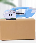Heavy Duty Electric Rechargeable PET PP Strapping Tool 3 In 1 Bander With Auto Cut And Hot Weld For Shipping Boxes And Pallets on cardboard box.