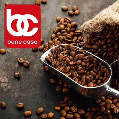 Silver scoop with coffee beans on a dark surface near a burlap sack, with a red 'bene casa' logo in the corner.