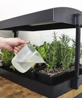 All In One Indoor Garden Kit With Dual T5HO Grow Lights And NanoTech Reflectors Auto Watering Mat in use with hand watering plants