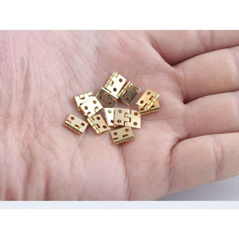 Top Shelf 50 Pack Mini Brass Hinges With A Seamless 180 Degree Swivel For Micro Crafts and Tiny Cabinet Fixes on a hand.