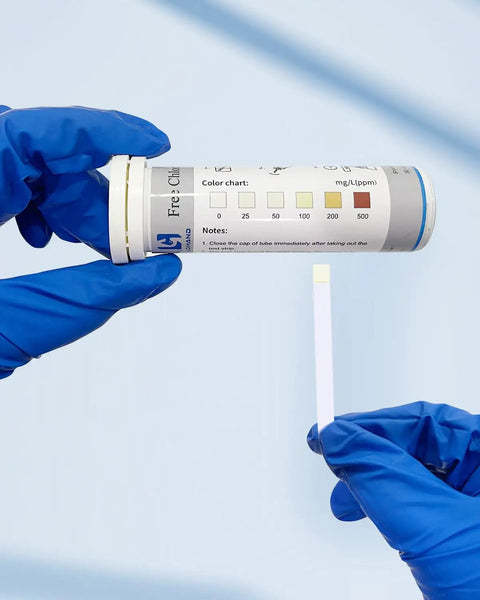 Person holding Chlorine Test Strips 0-500 PPM Pack of 100 for Restaurant Sanitizers and Bleach Disinfectants kit with blue gloves.