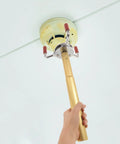 A hand holding a lightweight aluminum smoke transducer removal tool reaching towards a ceiling smoke detector.