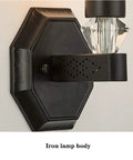 Dope Minimalist Black Wall Sconce With Rugged Iron Frame And Frosted Glass Shade providing a close view of the iron lamp body.