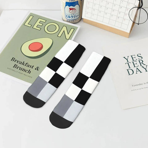 Black And White Checkerboard Straight Tube Socks Crafted From Buttery Soft Polyester For Elite Breathability And Quick Dry Comfort A Dead Set Classic For The Daily Grind Or Weekend Chill Sessions on a table with trendy decor.
