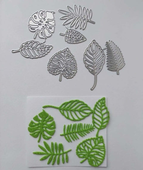 Totally Seven Piece Leaf Die Cut Set For Scrapbooking And Card Making with silver carbon steel leaf shapes and green stencil cutouts.