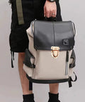 Front view of beige and black backpack with gold turn-lock clasp on flap and side zip pockets