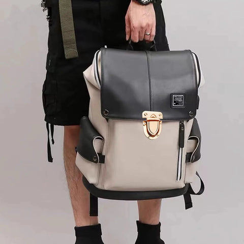 Front view of beige and black backpack with gold turn-lock clasp on flap and side zip pockets