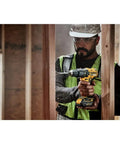 Worker using Compact Cordless Hammer Drill Kit With Brushless Motor, 20V Max Power, Half Inch Chuck, drilling through wood frame.