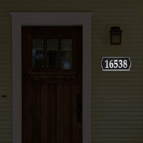 Reflective Address Numbers Sign With High Visibility Panels Weather Resistant Easy Mount For Front Porch Or Mailbox Post Boost Your Curb Appeal And Help Visitors Find Your Home At Night displayed beside a front door at night.
