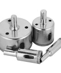 Close-up of 4-piece chrome hole saw set with arbors; two large hole saws and two smaller components visible