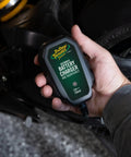 12V Smart Battery Charger And Maintainer For Powersports Riders Straight Up Restoration Of Motorcycles ATVs And UTV Batteries held in hand.