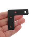 Close-up of a hand holding a black stainless steel L shaped corner brace, part of a 20 pack for picture frames and desk supports.