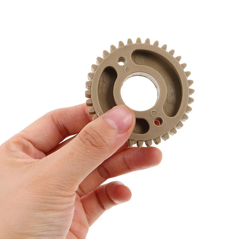 Beefed Up Replacement Gear For Electric Cup Sealing Machines Made From Durable Plastic, Helps Prevent Leaks And Spills, Stable Performance For Beverage Service, Easy Install And Long Lasting Wear. Grey plastic gear held by hand